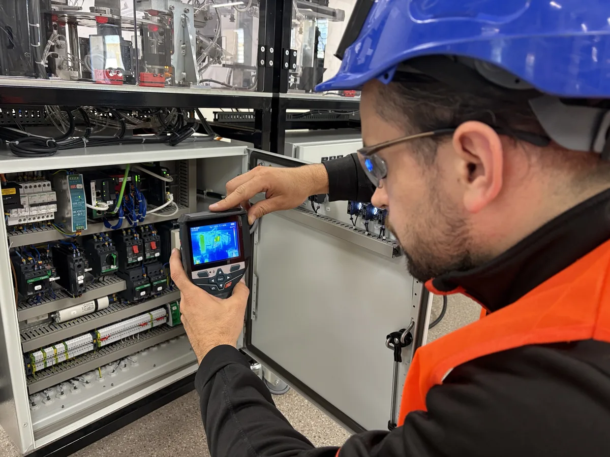 Relevé thermographique, caméra thermique en main devant une armoire
