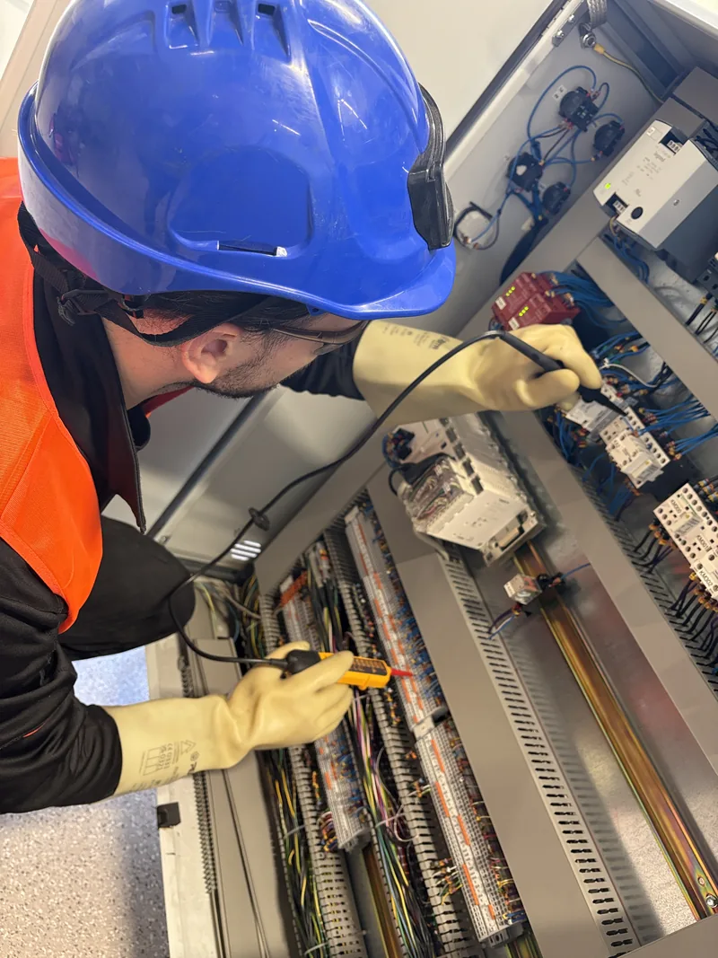 Mesures électriques dans une armoire, gants isolants et sonde de test